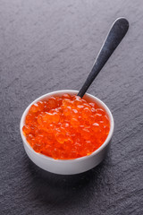 red caviar in a bowl on a dark stone background