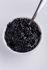 black caviar in a bowl on a white acrylic background