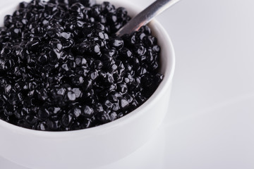 black caviar in a bowl on a white acrylic background