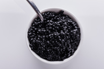 black caviar in a bowl on a white acrylic background