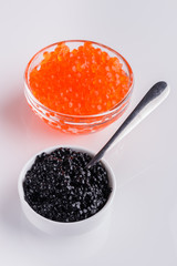 red and black caviar in a bowl on a white acrylic background