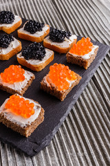Snack with red and black caviar on a stone plate