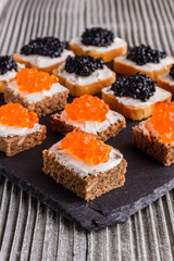 Snack with red and black caviar on a stone plate