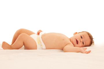 Hapy baby boy in playing on bed isolated over white