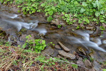 A fast stream in mountainous terrain. Water flowing in the river shown in a long exposure. Season of the spring.
