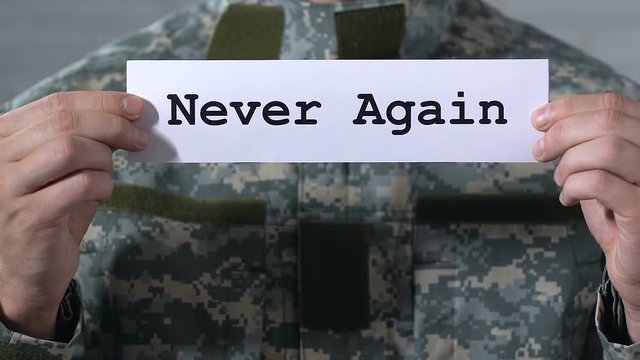 Never again written on paper in hands of male soldier, world peace concept