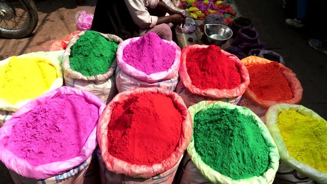 pan of large bags of bright colored powder for holi at the spice market of chandni chowk in old delhi, india