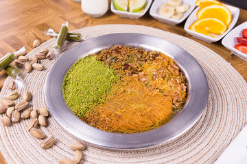 turkish dessert kunefe, kunafa, kadayif with pistachio powder and cheese hot eaten a sweet