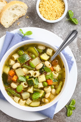 Minestrone Gemüsesuppe aus Zucchini, Sellerie, Karotte, Erbsen, Bohnen, Kartoffeln, Tomate, Spinat und Suppennudeln (Selektiver Fokus, Fokus auf die Suppe)