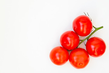 Organic red tomatoes with a green twig handful, lie on a white background. There is a place for text.