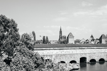 Tilt-shift lens over Les Ponts Couverts Gedeckte Brucken three bridges and four towers  in central Strasbourg with Notre-Dame cathedral in background and clear blue sky black and white
