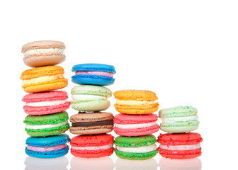 Macaron cookies in tiny white dishes stacked in graduated rows, colorful traditional french pastry isolated on reflective surface.