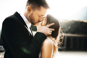 Close up portrait of a handsome young couple kissing in their wedding day against sunrise while...