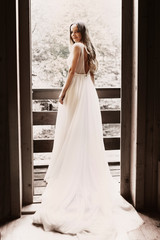 Full length portrait of a amazing caucasian bride sitting at balcony and looking at camera over the shoulder.