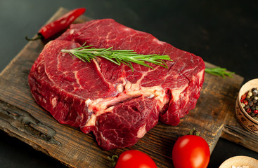 raw beef steak with herbs and spices on a stone background