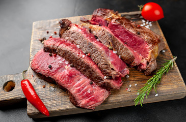 Grilled rib eye beef steak with herbs and spices on a stone background