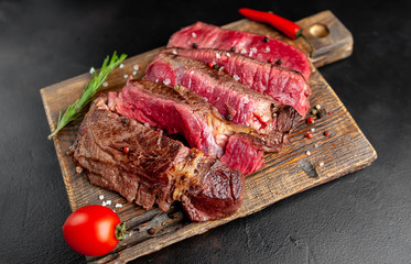 Grilled rib eye beef steak with herbs and spices on a stone background