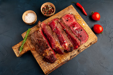 Grilled rib eye beef steak with herbs and spices on a stone background