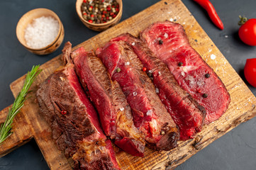 Grilled rib eye beef steak with herbs and spices on a stone background