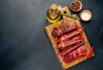 Grilled rib eye beef steak with herbs and spices on a stone background with copy space for your text
