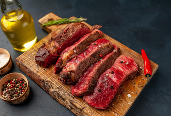 Grilled rib eye beef steak with herbs and spices on a stone background