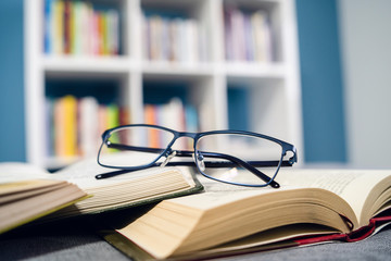 Reading glasses and pile stack of books reading and learning concept at home school study