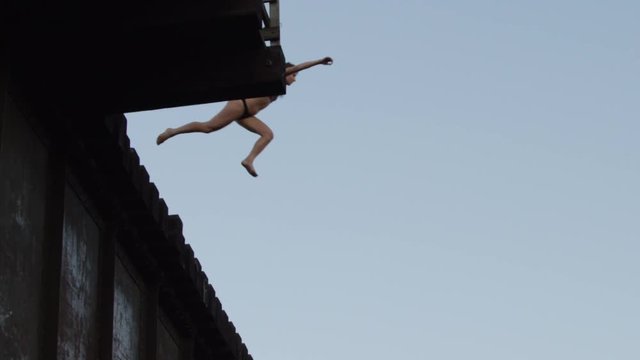 Woman jumping off of bridge into water fun diving extreme travel leisure