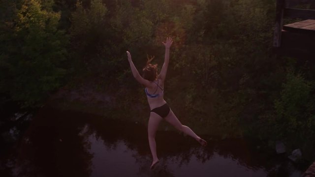 Woman jumping off of bridge into water fun diving extreme travel leisure