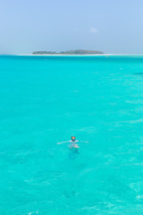 Woman snorkeling in clear shallow sea of tropical lagoon with turquoise blue water and coral reef, near exotic island. Mnemba island, Zanzibar, Tanzania. - obrazy, fototapety, plakaty