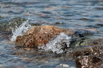 The sea waves rolling on the stony coast, a close up
