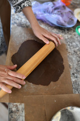 Mom rolls the dough. chocolate dough. Hands work with cake dough recipe preparation. Women's hands, Women's hands roll out the dough. Mom rolls dough on a kitchen board with a rolling pin
