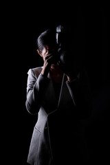 Fototapeta na wymiar Asian Woman Photographer hold camera with external flash point to shoot subject, wear gray suit. studio lighting black background isolated low key exposure, reporter journalist take photo celebrity