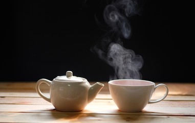 hot tea cup on wood table, Hot drink . with steam,warm soft light, dark background.Good morning Tea or Have a happy day message concept.