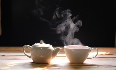 hot tea cup on wood table, Hot drink . with steam,warm soft light, dark background.Good morning Tea or Have a happy day message concept.