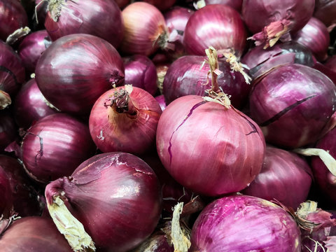 Detail of a group of red onions stacked in a supermarket. Delicious vegetable to accompany various dishes.