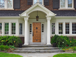 elegant wooden front door of large suburban house with gabled portico