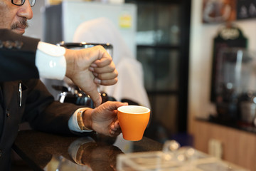 muslim customer businessman wearing black suit thumb down to a cup of coffee and complain at counter with young muslim barista businesswoman
