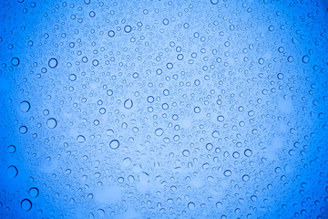 Rain droplets on blue glass background, Water drops on blue glass.