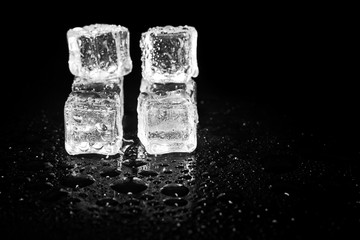 ice cubes reflection on black table background.