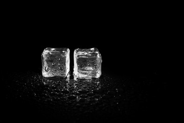 ice cubes reflection on black table background.