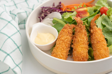 Close up crisp deep-fried prawns with salad in white bowl
