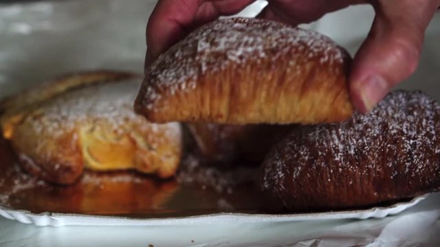 Close up hand of woman with age spots picking up a traditional famous italian neapolitan pastry called sfogliatella napoletana 4k