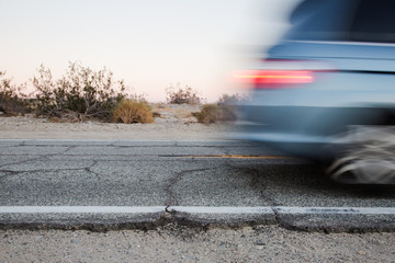 Speeding SUV Van on a Dry Cracked Desert Road at Sunset