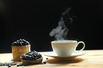 hot coffee and coffee beans with smoke on wooden table dark background