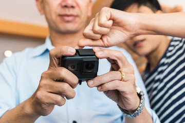 Two men people setting action camera video while holding for best cam recording