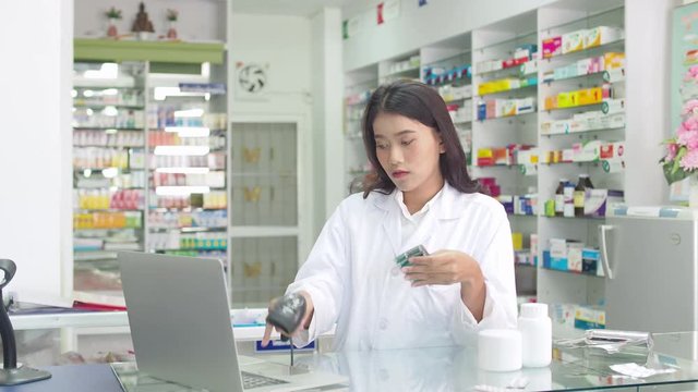 Beautiful pharmacist scanning for checking drug stock in drugstore