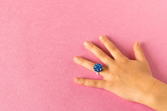 Funny ring on a little girl's hand. Isolated on pink background.