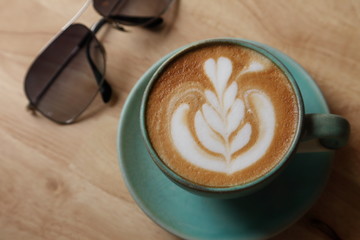 cup of latte coffee on wooden table with sunglasses with copy space