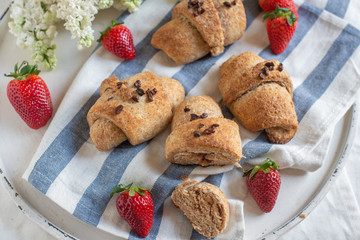 Homemade fresh golden croissants with strawberries and white lilac 