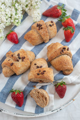 Homemade fresh golden croissants with strawberries and white lilac 